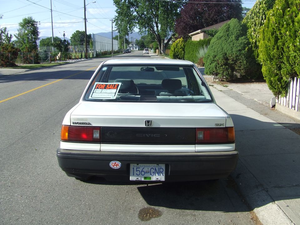 Rear view of a white Honda Civic DX sedan with a For Sale sign in the back window