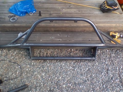 1978 Ford Bronco - Custom fabricated steel bumper with brush guard, likely for an off-road vehicle, resting on a wooden deck.
