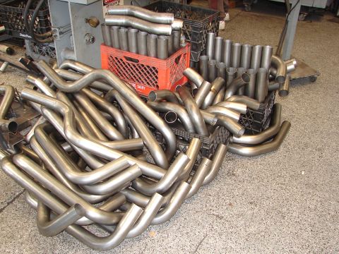 1992 Ford Taurus - Various exhaust pipe sections are piled on a workshop floor, some neatly stacked in crates.