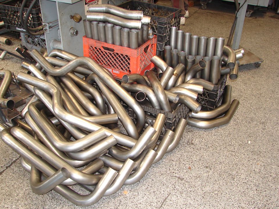 Pile of bent exhaust pipes in a workshop, some in crates