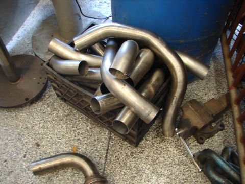 1992 Ford Taurus - Several bent exhaust pipes are piled in a crate, ready for installation or fabrication.