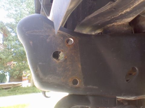 1978 Ford Bronco - Close-up view of a heavily rusted vehicle frame and bumper assembly.