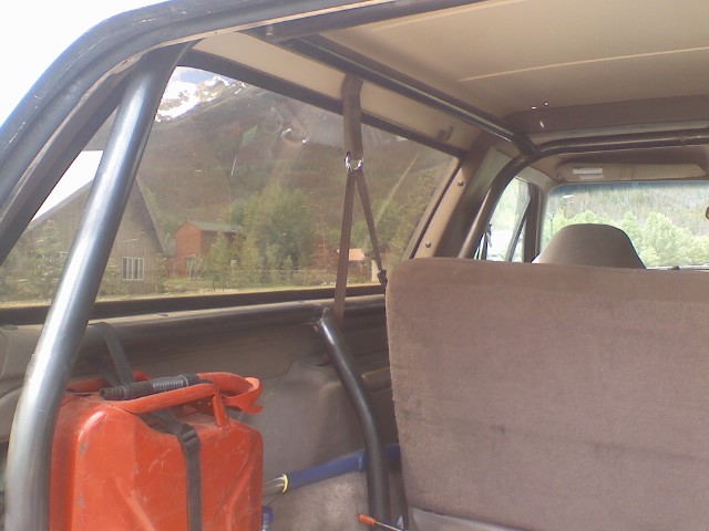 Bare-steel roll bar behind tan rear bench in Bronco with red jerry can strapped in