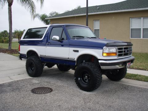 1996 Ford Bronco - This lifted Ford Bronco is parked on a residential street with a house in the background.