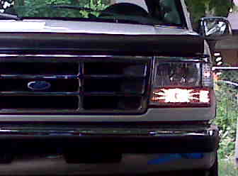 1995 Ford Bronco - Front view of a white Ford Bronco, showing the grille and headlight assembly. The vehicle appears to be from the early to mid-1990s.