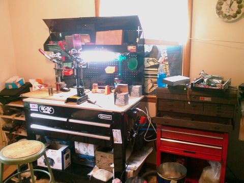 1985 Ford F-150 - A cluttered workbench area with tools, equipment, and storage units is illuminated by overhead lights.
