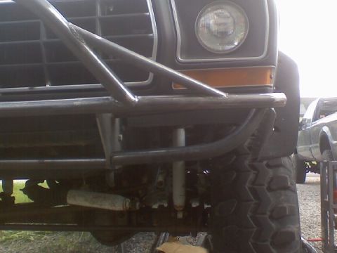 1978 Ford Bronco - Front view of a 1978 Ford Bronco modified with a roll cage and large tires, with another truck in the background.
