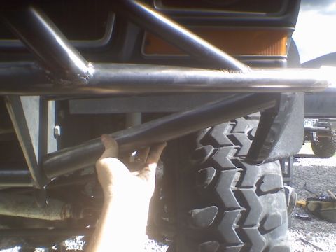 1978 Ford Bronco - A hand is shown adjusting a metal bar on a custom roll cage attached to an off-road vehicle.