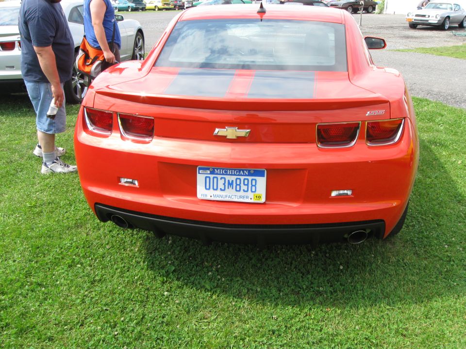 Rear view of a red Chevrolet Camaro with dual black racing stripes and a Michigan license plate reading 003M898