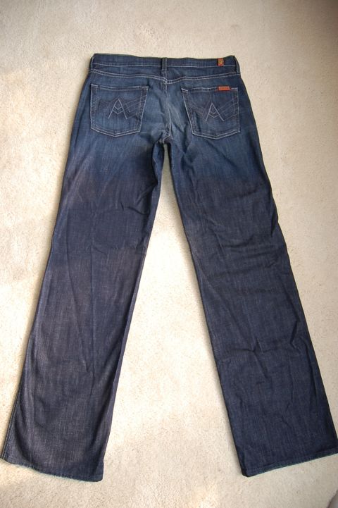 1968 Chrysler Town & Country - A pair of dark wash denim jeans are laid out flat on a carpeted surface, showing the back view with embroidered pockets.