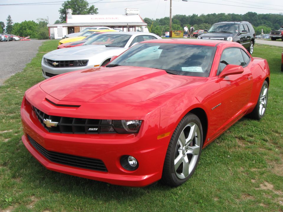 Red Chevrolet Camaro SS parked on grass with other cars in background