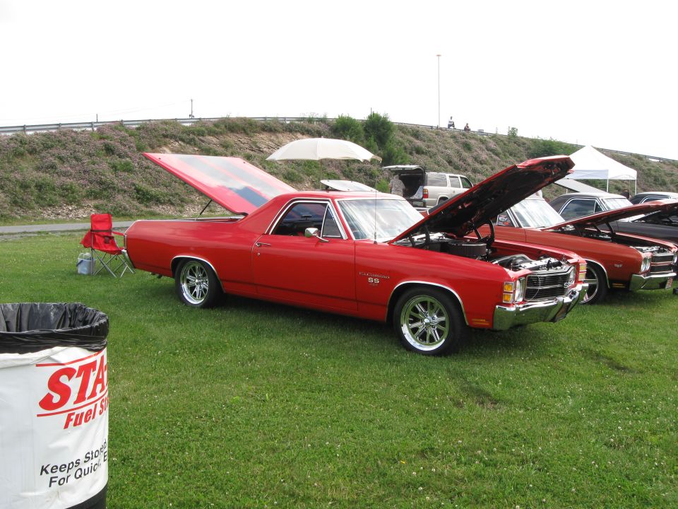 Red 1970 Chevrolet El Camino SS with hood and trunk open, parked on grass next to other cars