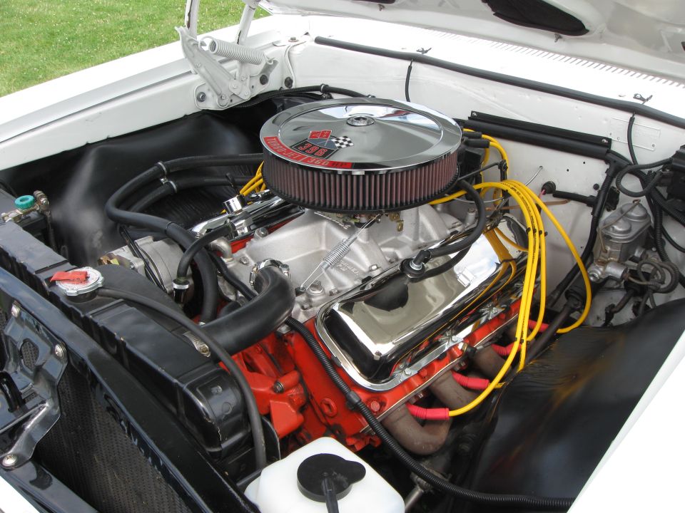 V8 engine bay with chrome air cleaner, red engine block, and yellow spark plug wires