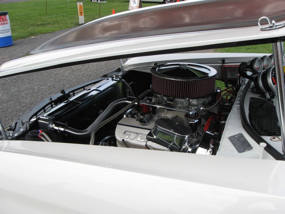 Engine bay of a white car showing a V8 engine with a chrome air cleaner and "572" inscribed on the valve cover