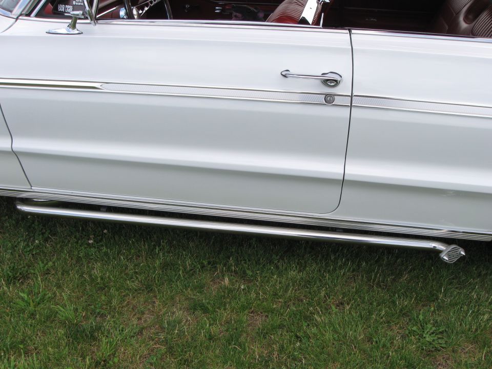 Side view of a white classic car with chrome trim and side pipes