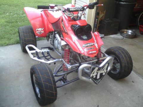 2004 Honda TRX 400 EX - A red ATV with racing tires and a prominent number 414 on its front bumper sits on a concrete surface.