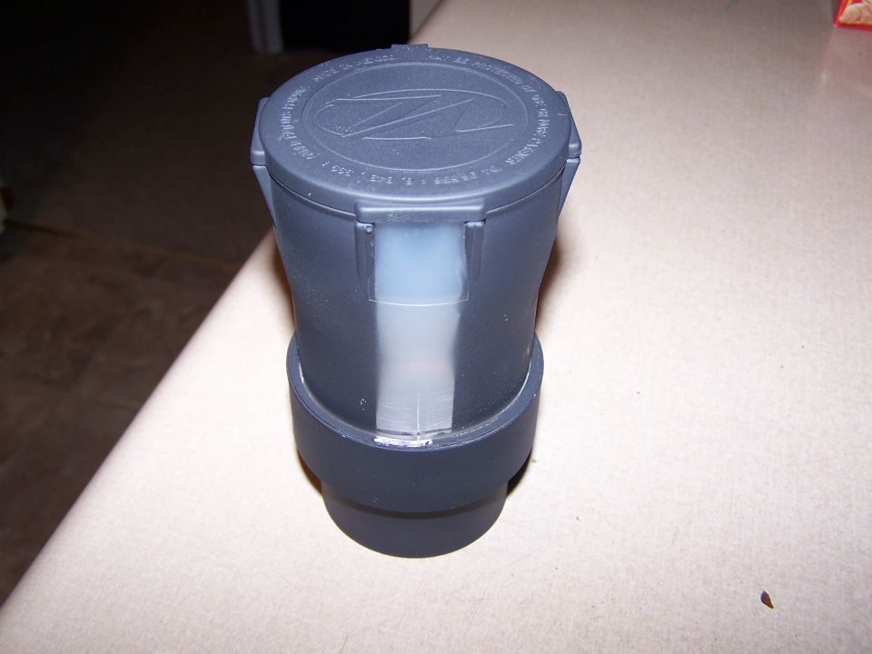 Dark gray fluid reservoir cap with a Z logo and some text around the edge