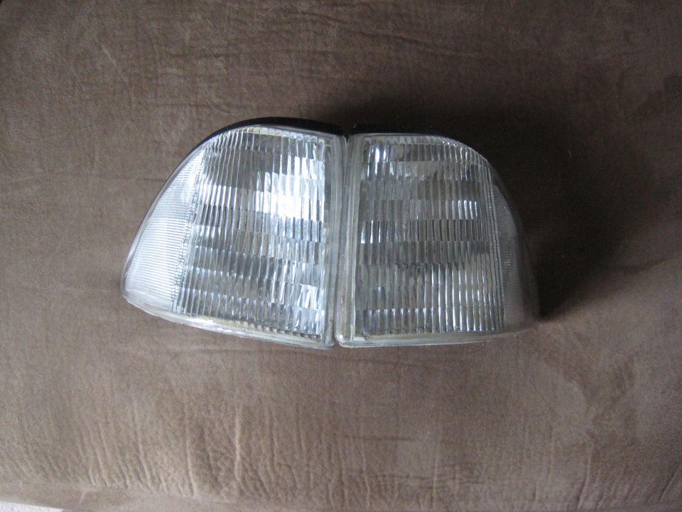pair of clear plastic car headlights with ribbed lenses, mounted on a brown textured surface