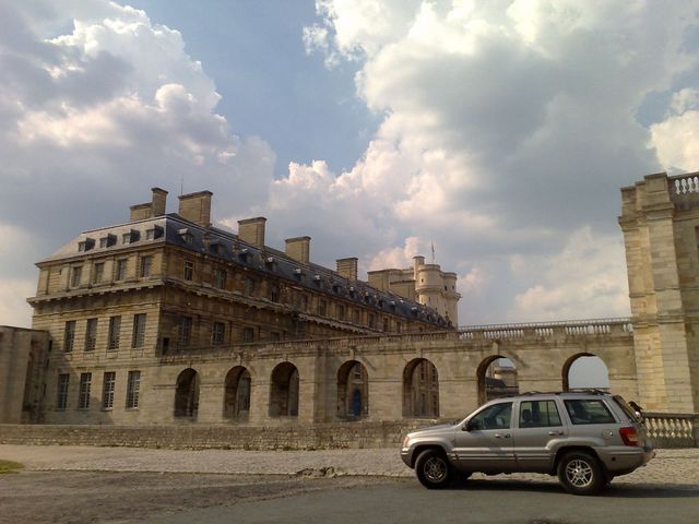 Silver Jeep Grand Cherokee parked in front of a large stone building with arched walkways