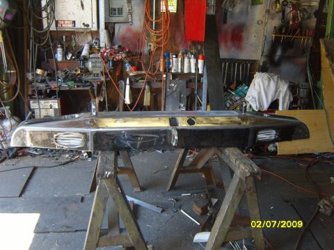 1989 Ford Bronco - chrome bumper sits across sawhorses in a workshop full of tools and wiring; image dated 02/07/2009.