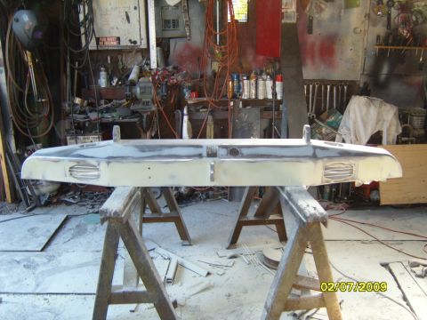 1989 Ford Bronco - A vehicle bumper, possibly from a Ford Bronco, is undergoing repair work in a cluttered garage setting.