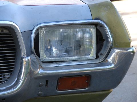 1973 Ford Ranchero - The front corner of a 1973 Ford Ranchero shows its chrome bumper, headlight assembly, and marker light.