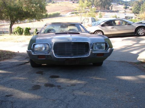 1973 Ford Ranchero - Front view of a car with a large grille and dual headlights, parked outdoors with other vehicles visible.