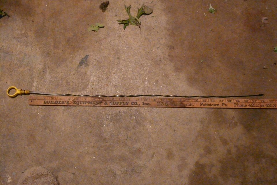 Yellow-handled oil dipstick next to a ruler