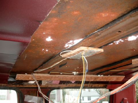 1990 Ford Bronco - The interior ceiling of the vehicle shows significant rust and exposed wiring, with wooden supports holding up sections.