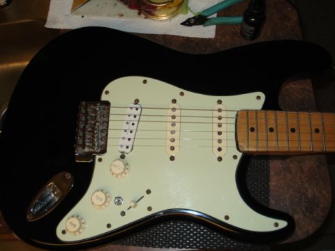 1979 Chevrolet C/K Pickup - A black electric guitar with three single-coil pickups and a light green pickguard is shown.