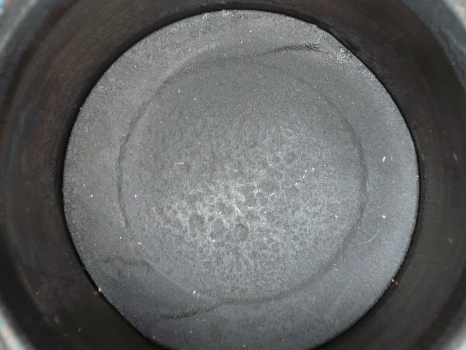 Piston top inside engine cylinder, showing carbon buildup