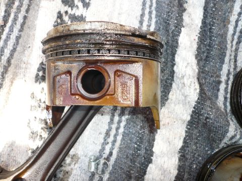 1975 Ford Ranchero - A close-up view of a used engine piston and connecting rod, showing signs of wear and oil residue.