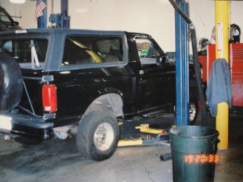 1995 Ford Bronco - Side view of a black 1995 Ford Bronco on a lift inside a workshop.