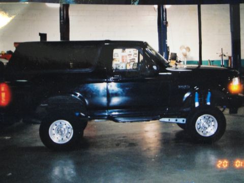 1995 Ford Bronco - Side view of a black SUV with custom suspension and wheels.