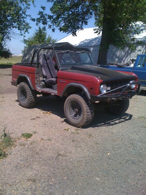 1968 Ford Bronco - A red 1968 Ford Bronco sits parked outdoors with a soft top and a custom front bumper.