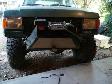 1990 Ford Bronco - Front view of a green Ford Bronco with a winch and aftermarket bumper.