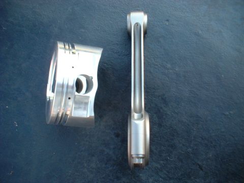 1968 Ford Galaxie - A piston and connecting rod are displayed on a dark blue surface, with website text visible in the corner.
