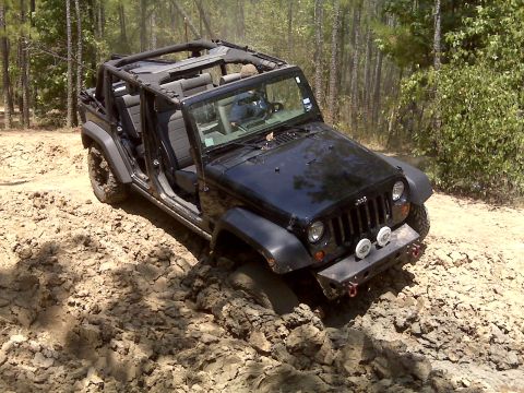 2008 Jeep Wrangler - 2008 Jeep Wrangler navigating a muddy off-road trail with doors and roof removed.