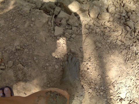 2008 Jeep Wrangler - A foot is submerged in mud, surrounded by dry, rocky terrain. A shadow indicates overhead obstruction.