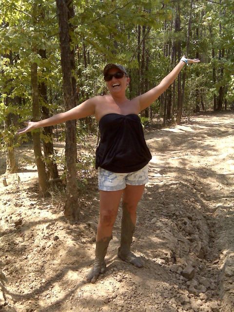 2008 Jeep Wrangler - A woman poses with her arms wide open in a muddy, wooded environment.