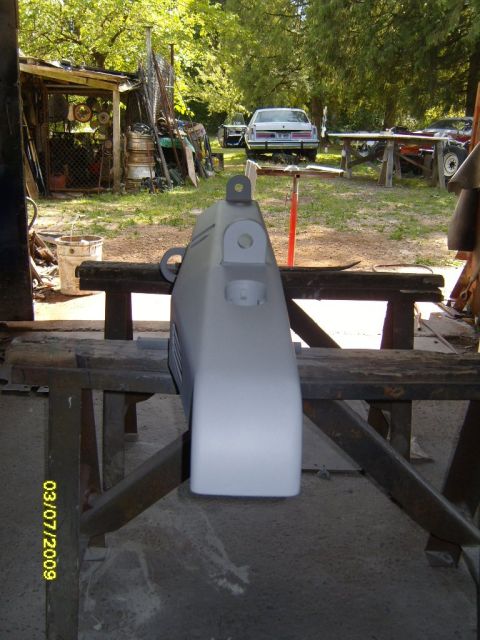 1989 Ford Bronco - A vehicle bumper part is prepped for painting in an outdoor workshop setting.