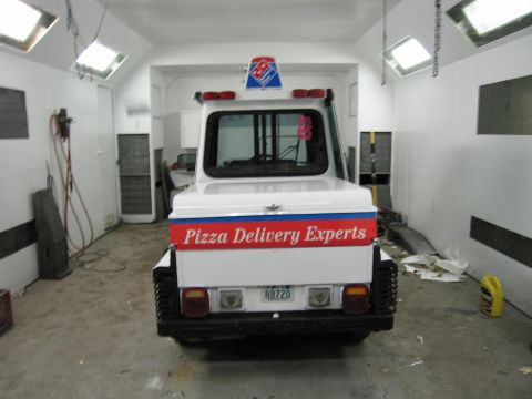 2001 Ford Crown Victoria - A white pizza delivery vehicle is parked in a garage with overhead lights.