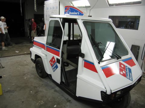 2001 Ford Crown Victoria - A white three-wheeled Domino's Pizza delivery vehicle is shown with its doors open in a garage setting.