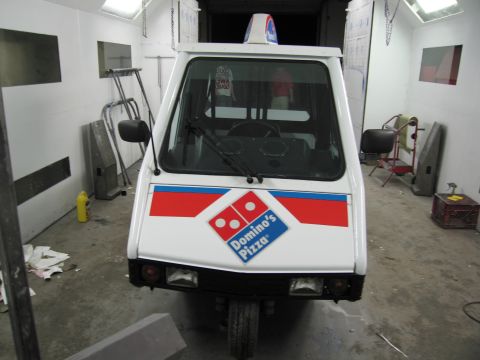 2001 Ford Crown Victoria - A Domino's Pizza delivery trike is parked inside a garage or workshop.