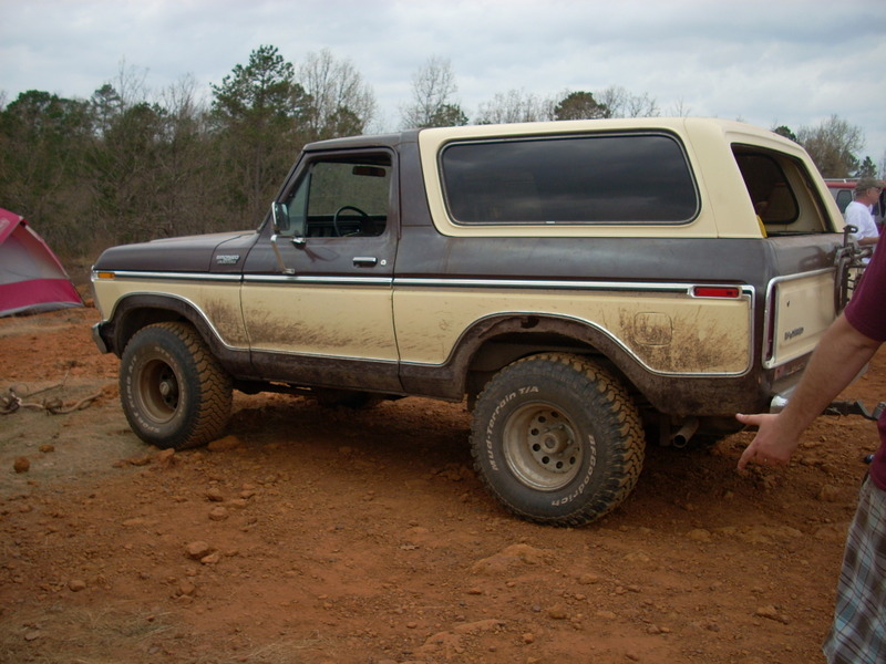 Brown and tan Ford Bronco with off-road tires parked on dirt