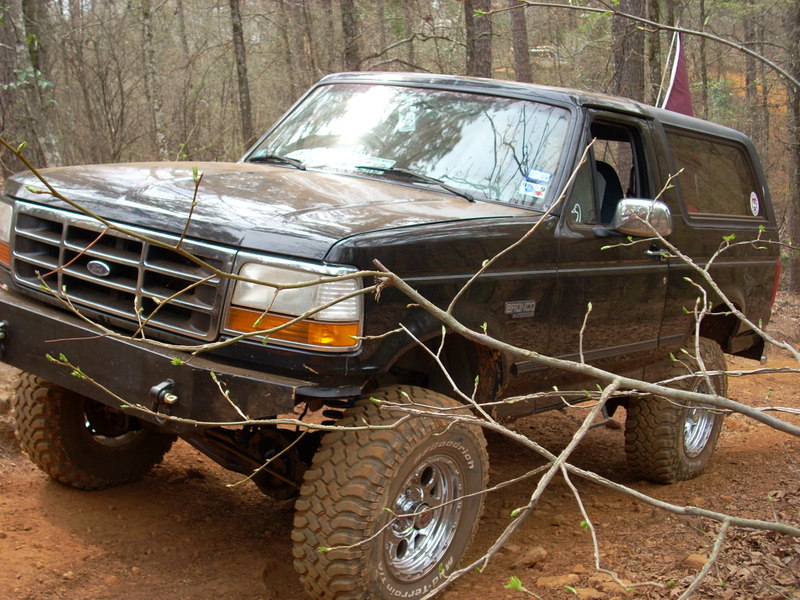 Black Ford Bronco with aftermarket bumper and off-road tires on a dirt trail