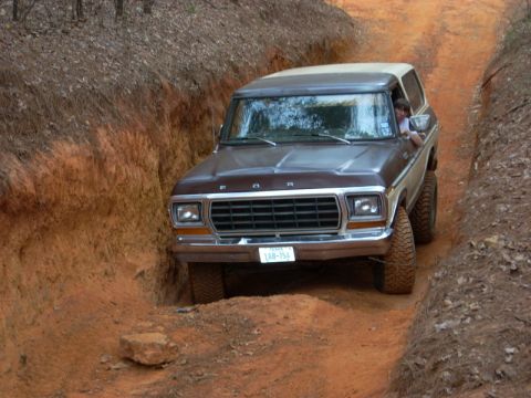1996 Ford Bronco - A vintage Ford Bronco navigates a narrow, rutted dirt trail.