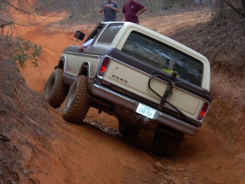 1996 Ford Bronco - This Ford Bronco is navigating a steep, muddy trail with its tires angled.