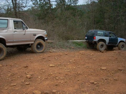 1996 Ford Bronco - A tan 1992 Ford Bronco tows a modified SUV through an off-road trail.