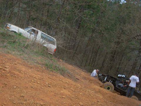 1996 Ford Bronco - A white 1996 Ford Bronco is seen partially off-road on a steep dirt incline, with another off-road vehicle and people visible below.